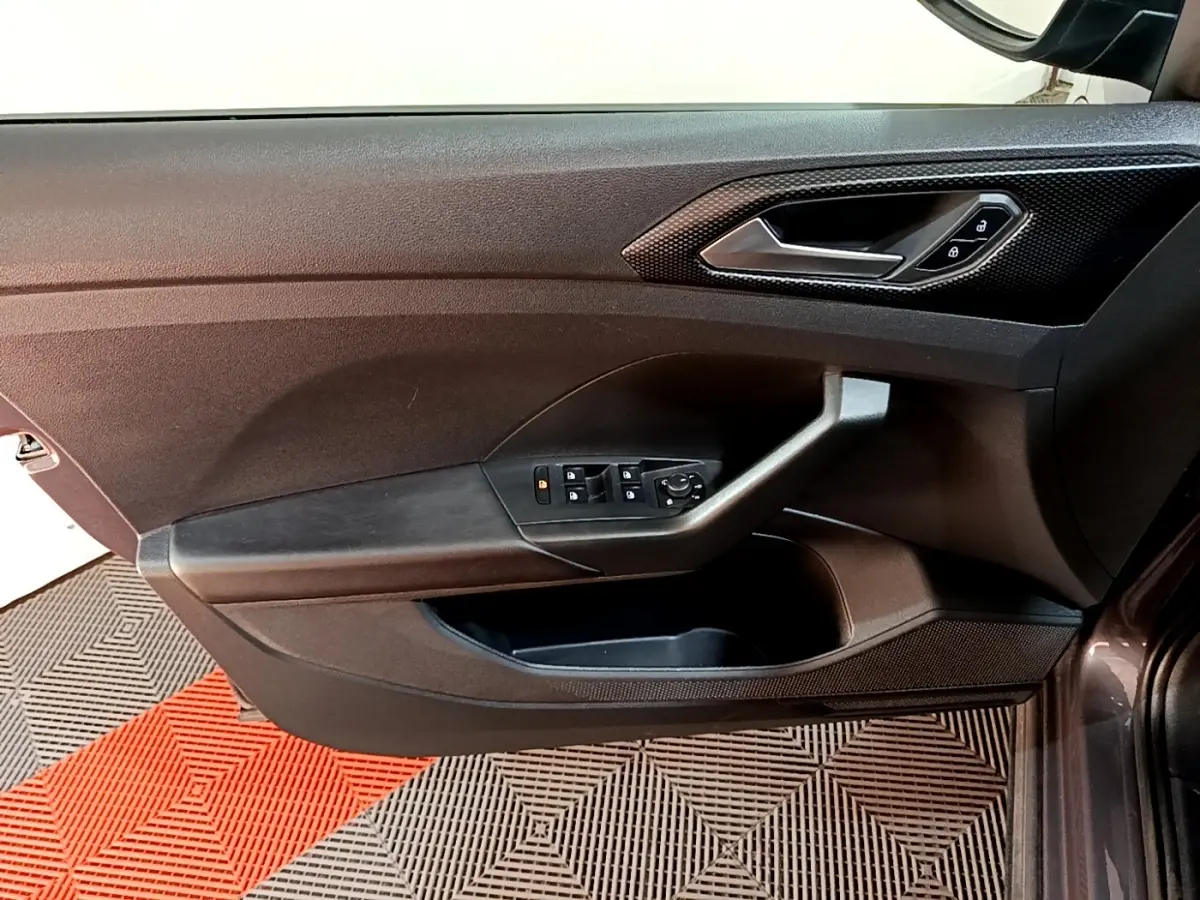Vue rapprochée de la porte avant droite gris foncé du Volkswagen T-Cross 2023 avec commandes de vitres et verrouillage.