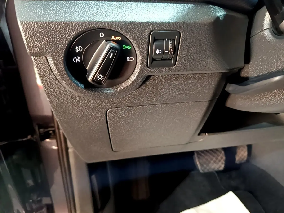 Gros plan sur le panneau de commande des phares côté gauche du Volkswagen T-Cross gris foncé, intérieur conducteur.