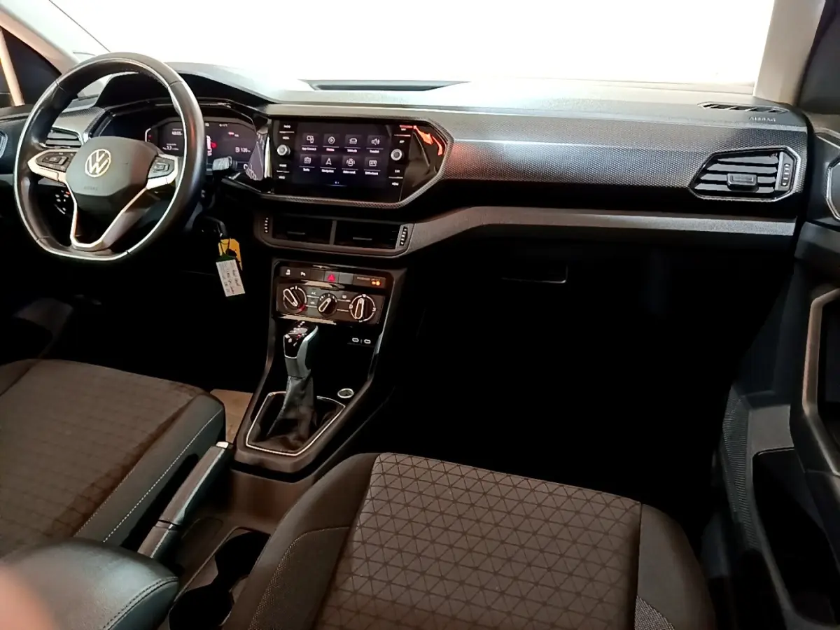 Intérieur du Volkswagen T-Cross 2023, vue de face côté conducteur, volant cuir multifonctions et écran tactile central.