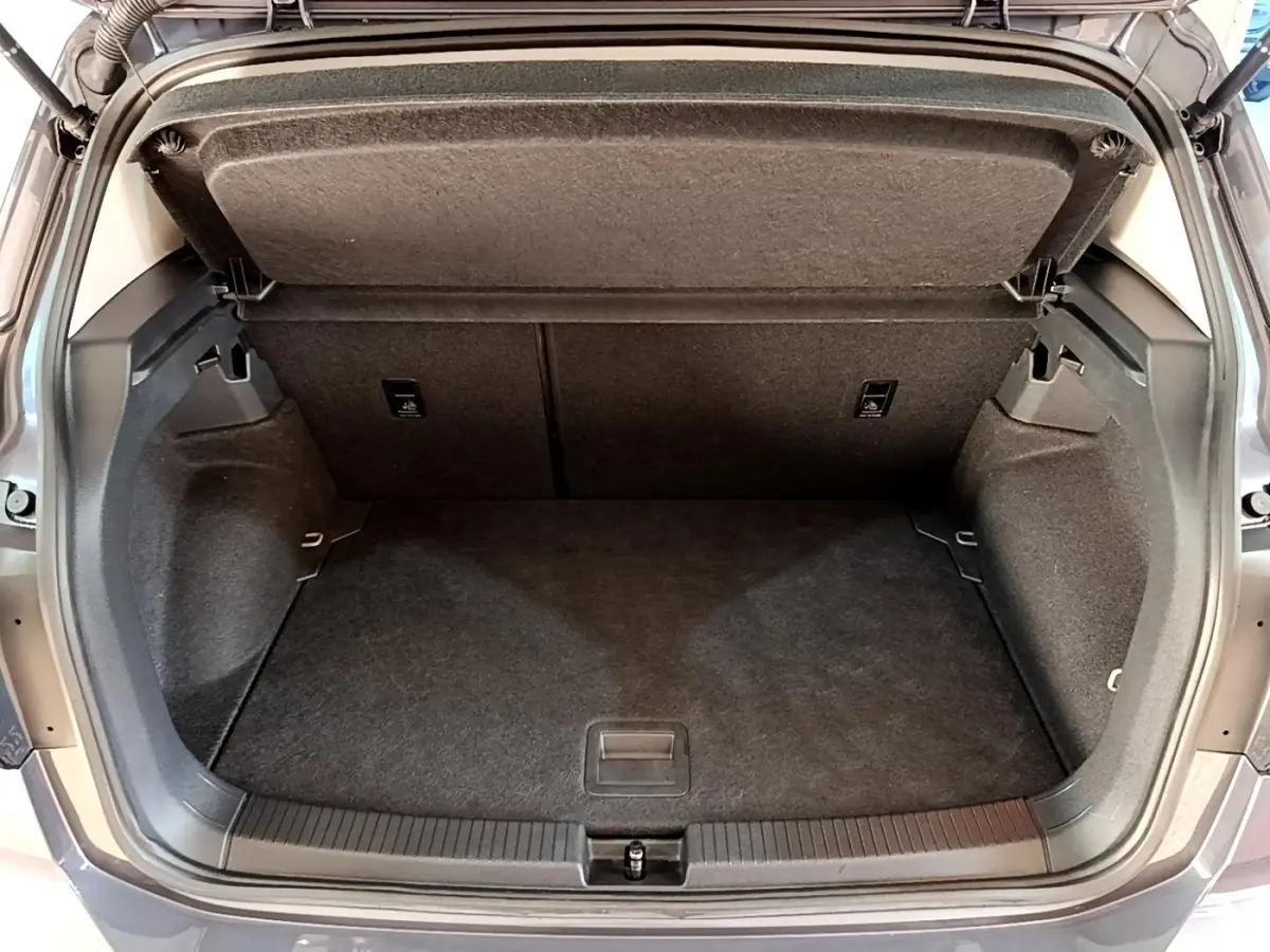 Vue arrière ouverte du coffre gris foncé du Volkswagen T-Cross 2023, montrant l'espace de rangement vide et la tablette de séparation.