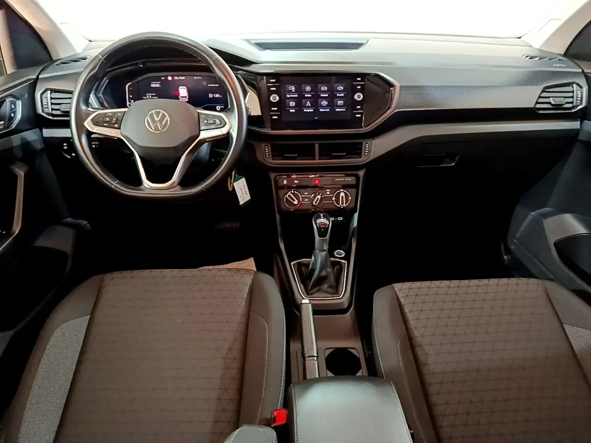 Vue intérieure avant du Volkswagen T-Cross 2023, volant cuir multifonctions et tableau de bord avec écran tactile central.