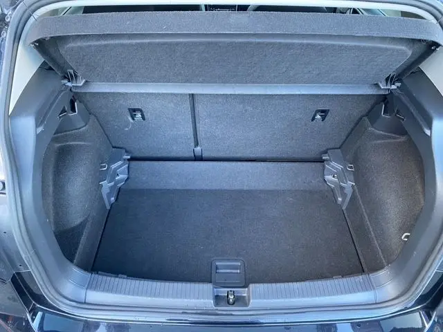 Coffre ouvert vu de l'arrière d'un Volkswagen T-Cross noir, montrant un espace de chargement propre et bien fini.