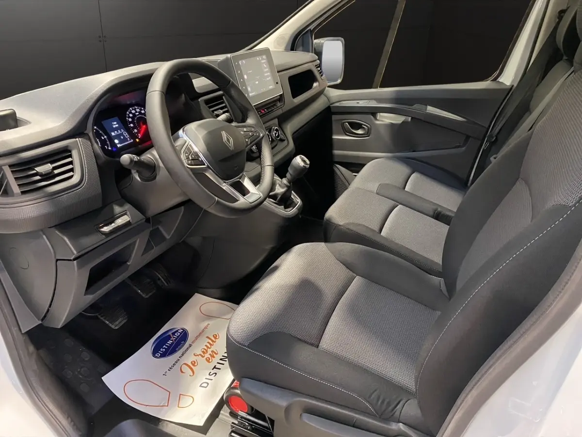Vue intérieure côté conducteur du Renault Trafic Fourgon blanc 2025, montrant le volant multifonctions et la console centrale.