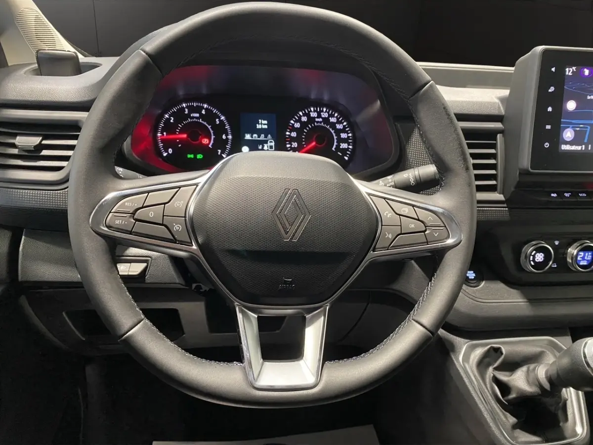Vue intérieure centrée sur le volant multifonctions noir du Renault Trafic Fourgon avec tableau de bord et écran tactile.