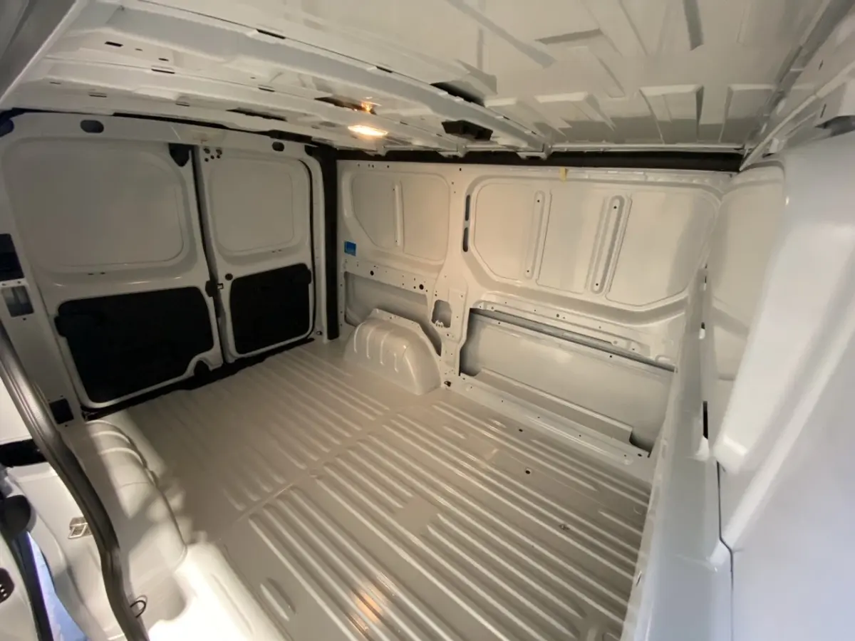 Vue intérieure du fourgon Renault Trafic blanc, montrant l’espace de chargement vide avec cloison pleine à l’arrière.