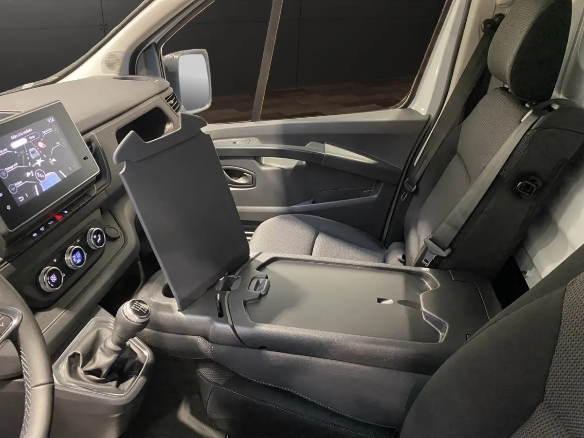 Vue intérieure côté passager du Renault Trafic Fourgon 2025 blanc, montrant la console centrale relevée et tableau de bord numérique.