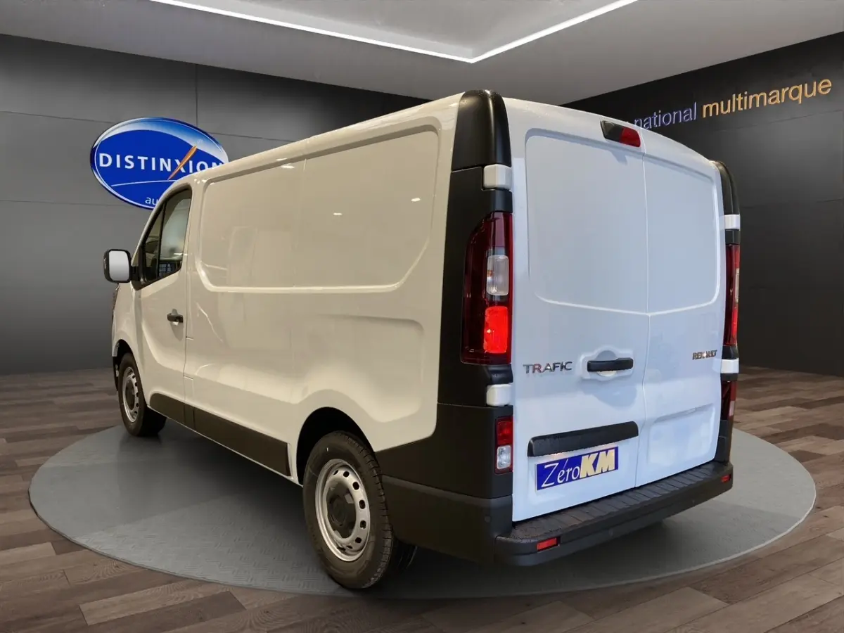 Vue 3/4 arrière droite du fourgon blanc Renault Trafic L1H1 avec portes arrière fermées et jantes acier.