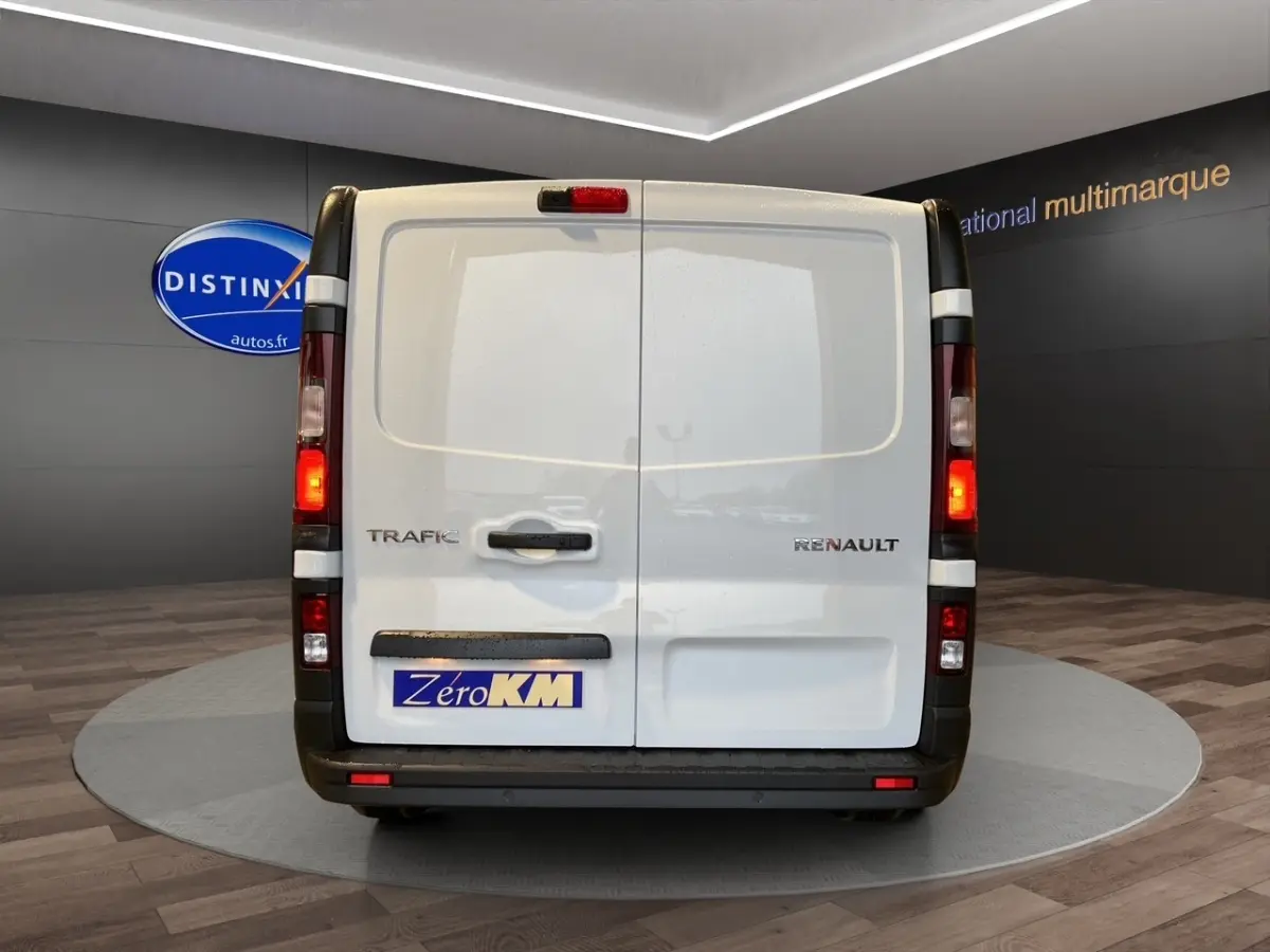Vue arrière du Renault Trafic Fourgon blanc, portes battantes fermées avec feux arrière allumés en intérieur showroom.