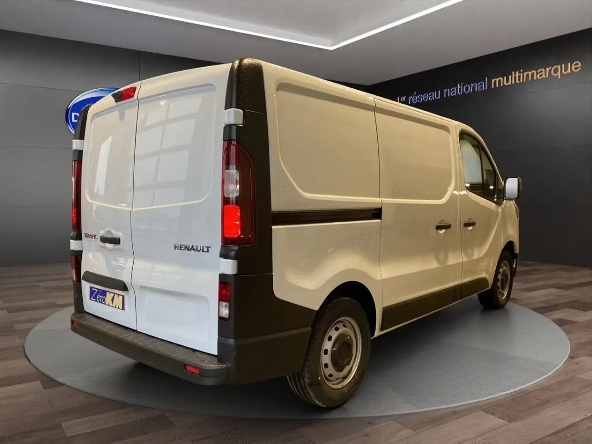 Vue 3/4 arrière droite du fourgon blanc Renault Trafic Fourgon L1H1 avec portes arrière battantes et feux arrière verticaux.