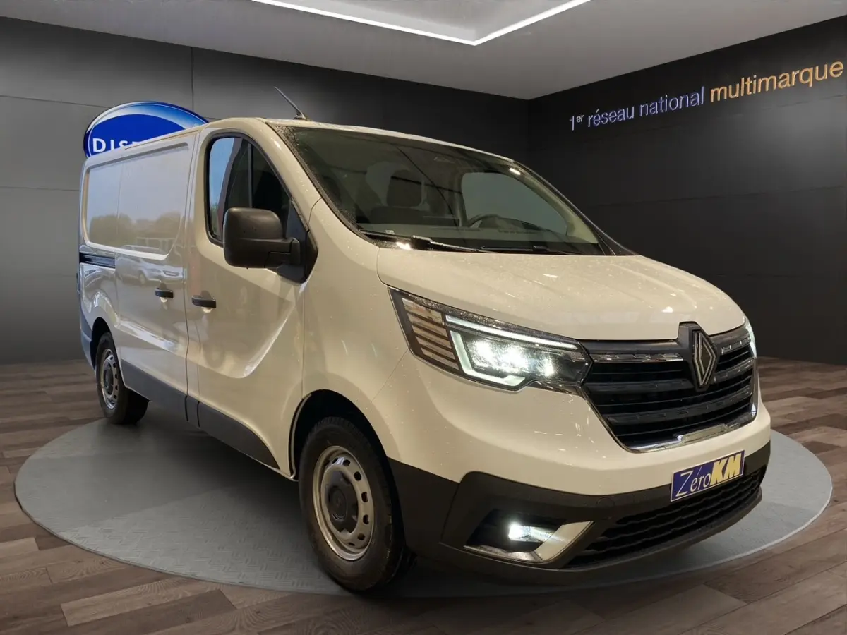 Renault Trafic Fourgon blanc en 3/4 avant droit, phares LED allumés et calandre noire distinctive.