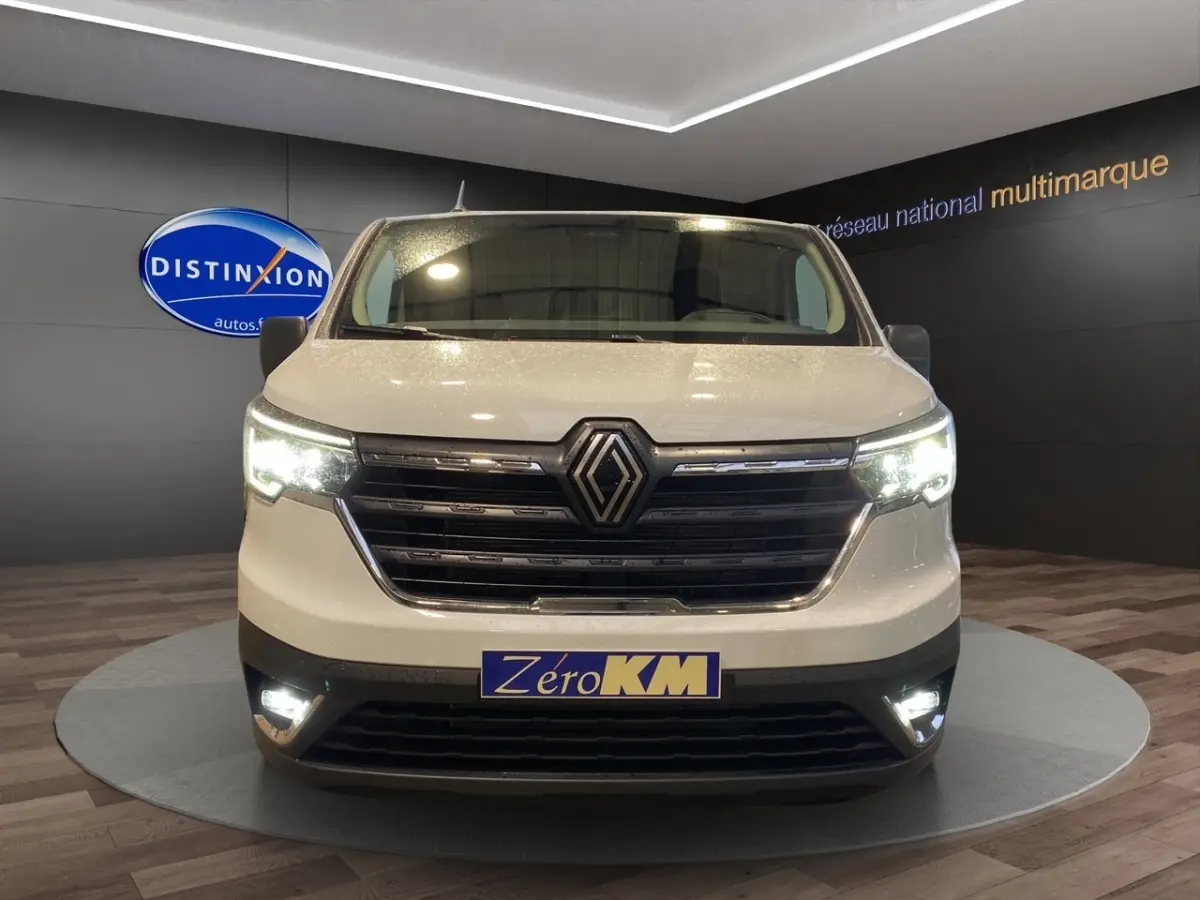 Vue frontale du Renault Trafic Fourgon blanc 2025 avec phares LED allumés en showroom.