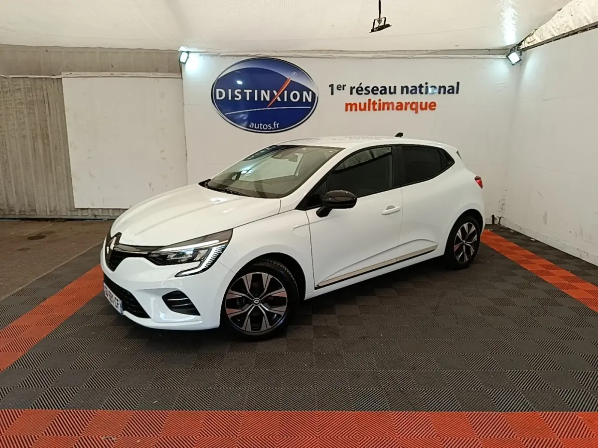 Renault Clio blanche vue 3/4 avant droit, avec jantes noires et rétroviseurs noirs dans un showroom.