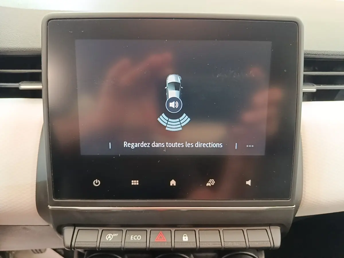 Écran tactile central de la Renault Clio blanc 2023 affichant une alerte de surveillance des alentours.