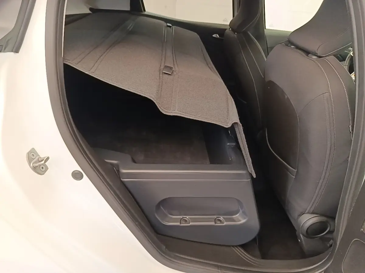 Vue intérieure côté gauche arrière de la Renault Clio blanche 2023, coffre sous banquette arrière relevé.