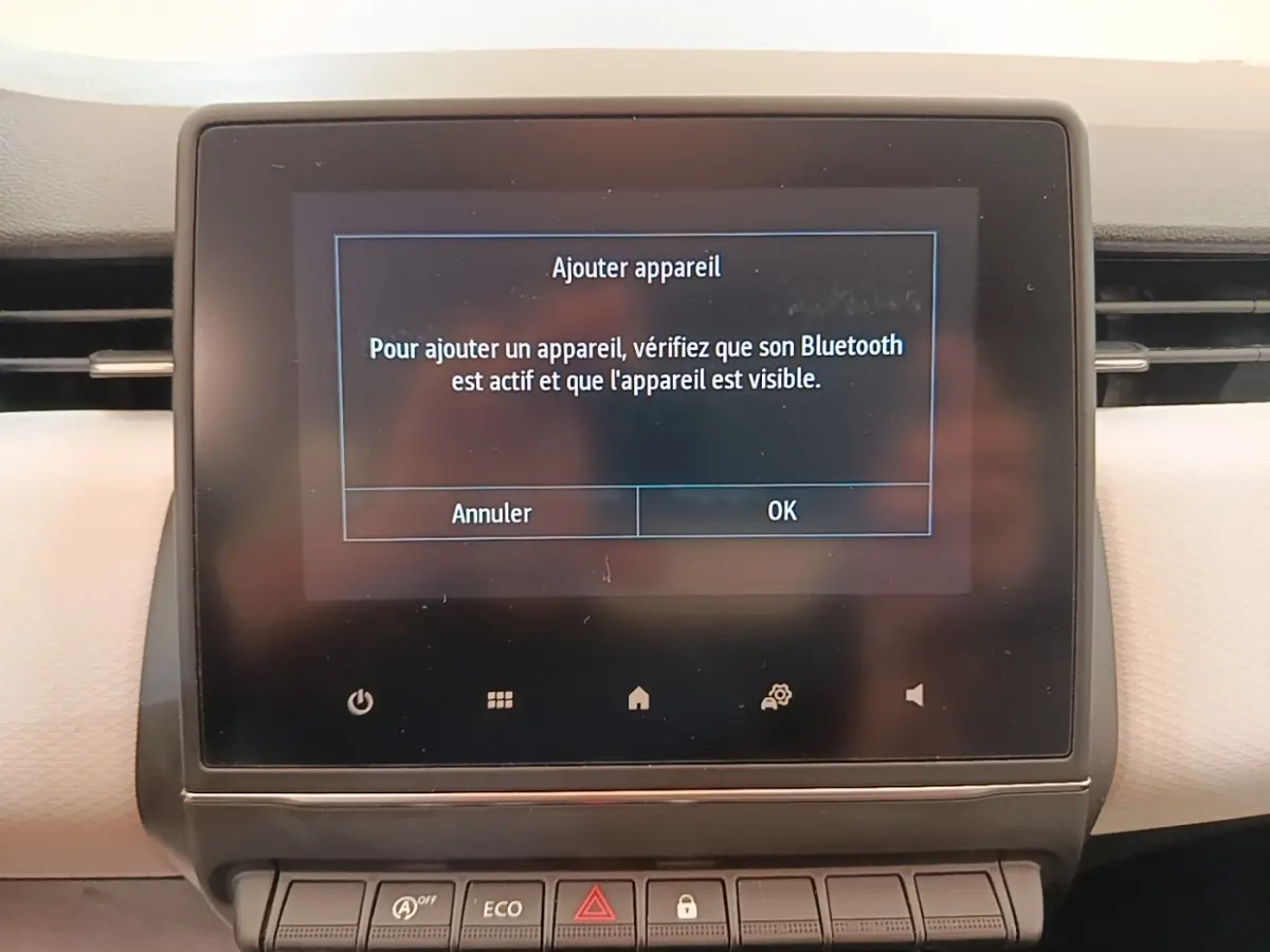 Écran tactile central affichant la connexion Bluetooth dans l'habitacle d'une Renault Clio blanche, vue de face.