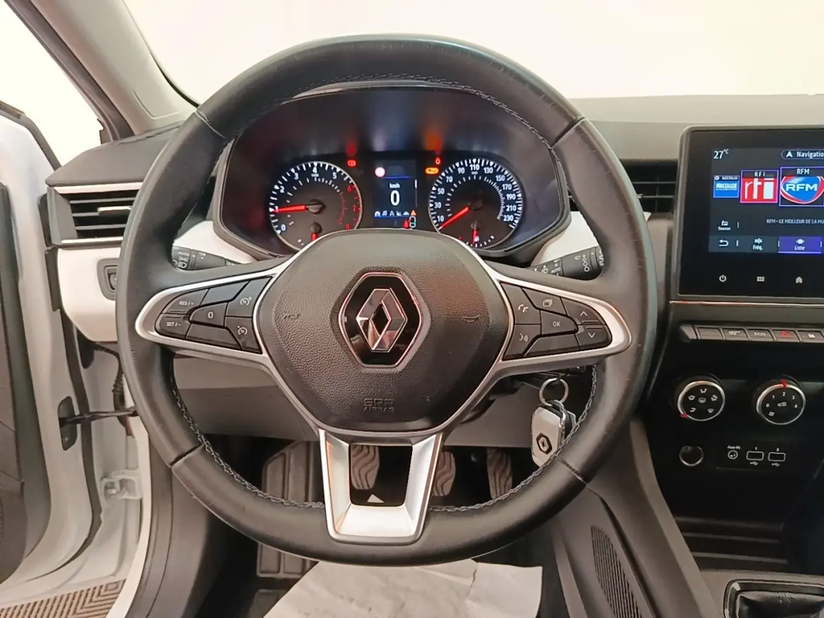 Vue rapprochée du volant cuir noir multifonctions d’une Renault Clio blanche 2023 avec tableau de bord et écran tactile.
