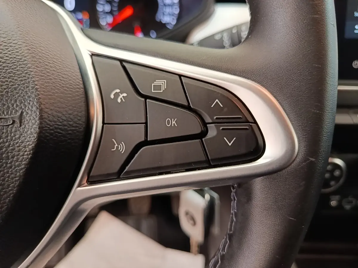 Gros plan sur le côté droit du volant cuir synthétique de la Renault Clio blanc, avec commandes multifonctions visibles.