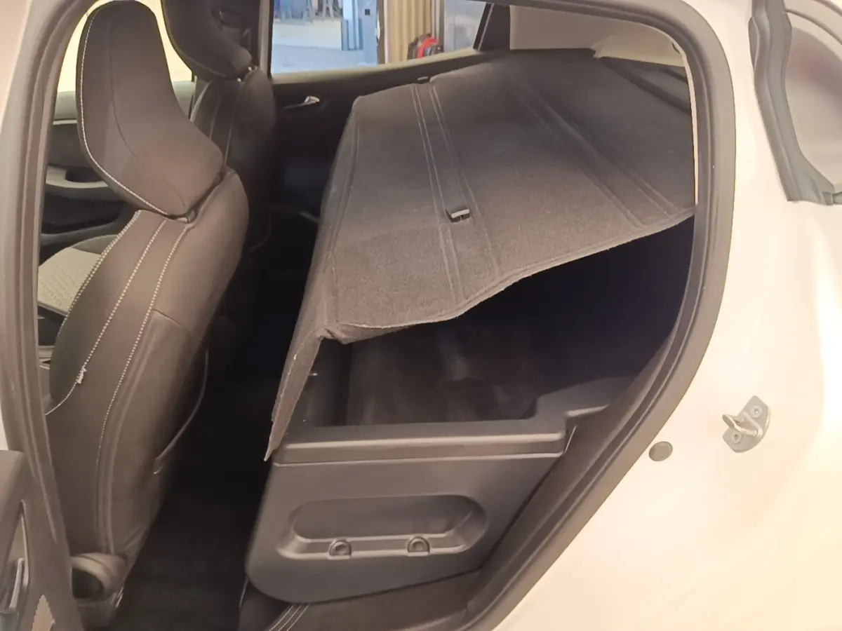 Vue côté droit arrière d'une Renault Clio blanche 2023 montrant le coffre de rangement sous le plancher relevé.