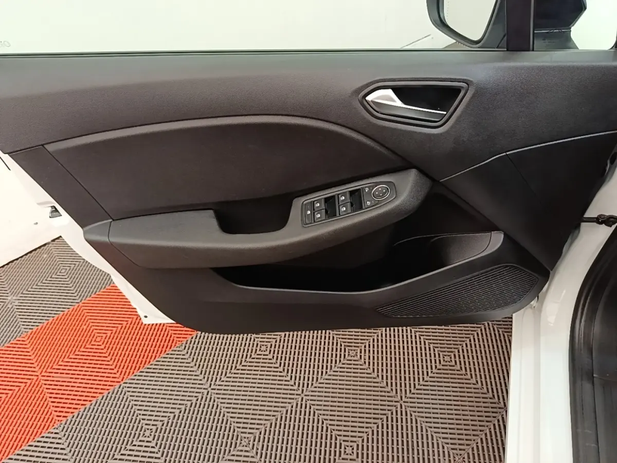 Vue intérieure de la porte avant gauche blanche de la Renault Clio 2023 avec commandes électriques et poignée argentée.