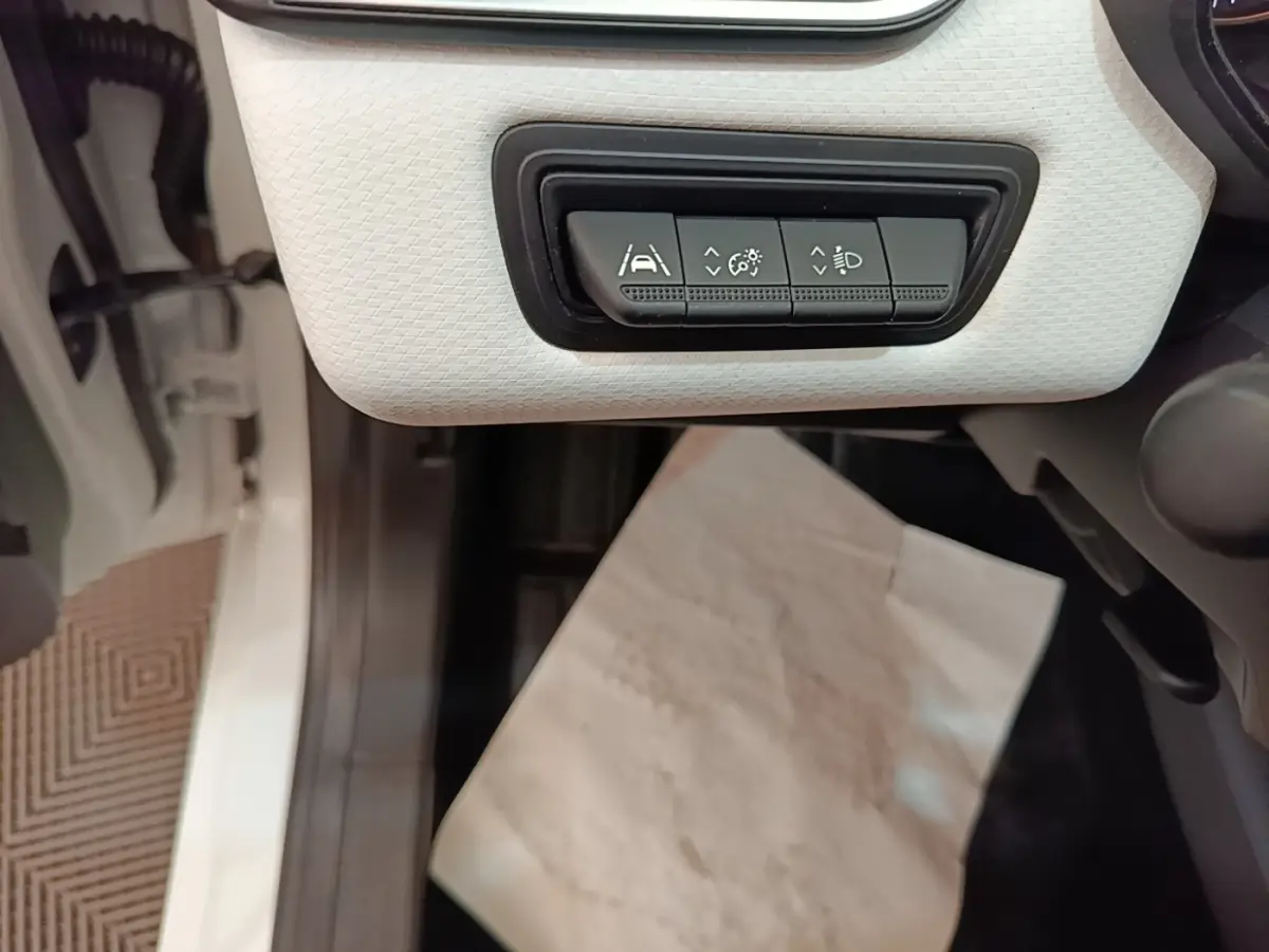 Vue rapprochée des commandes d’aide à la conduite sur panneau blanc à gauche du volant dans une Renault Clio blanche 2023.