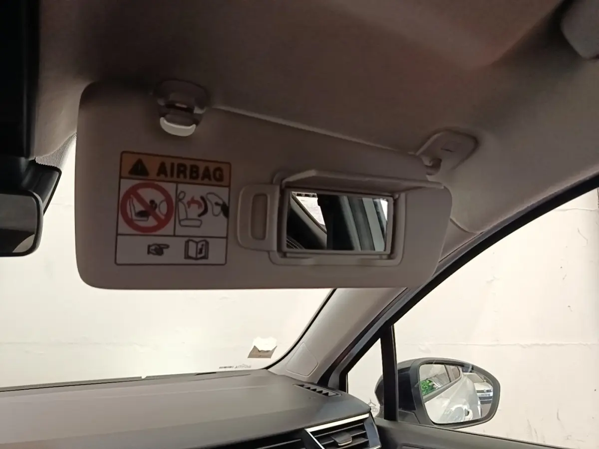 Intérieur de Renault Clio blanc 2023 vu côté passager, avec pare-soleil ouvert et miroir de courtoisie visible.