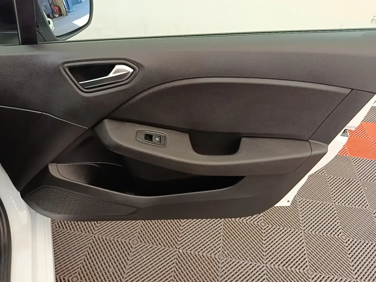 Vue rapprochée de la porte avant gauche noire d’une Renault Clio blanche, avec poignée intégrée et commande de fenêtre.