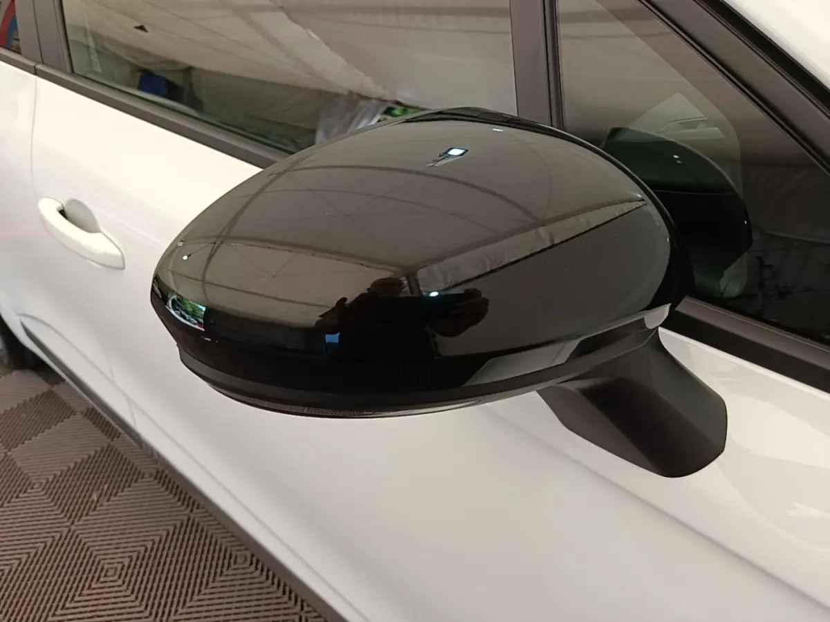 Gros plan sur le rétroviseur extérieur noir du côté gauche d'une Renault Clio blanche, version 2023.