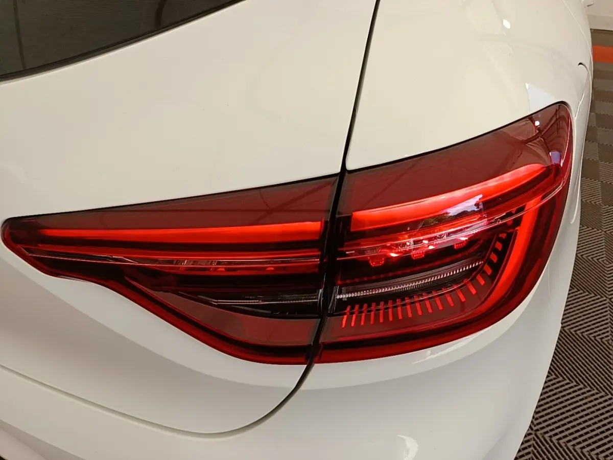 Gros plan sur le feu arrière droit rouge d’une Renault Clio blanche 2023, mettant en valeur ses lignes modernes.