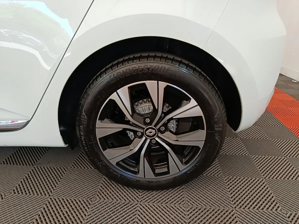 Gros plan sur la roue arrière droite blanche d’une Renault Clio 2023 avec jante alliage noire et argentée.
