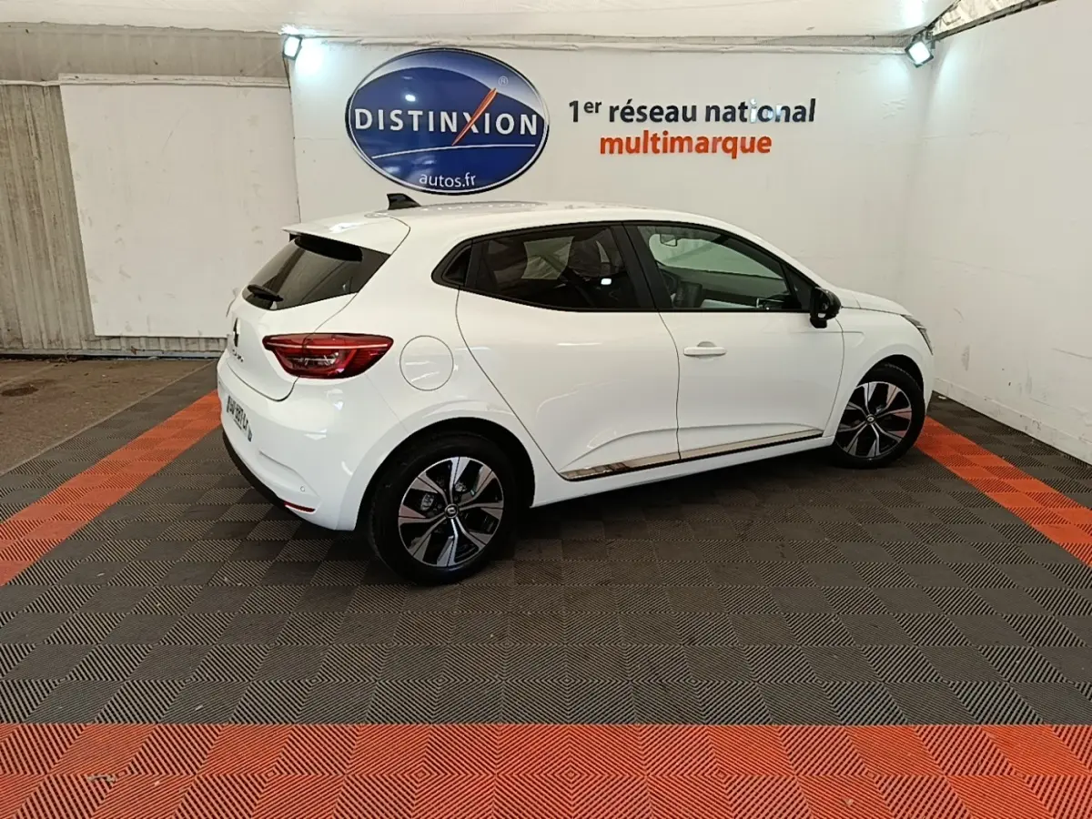Renault Clio blanche vue de profil droit en intérieur, avec jantes alliage et vitres teintées.