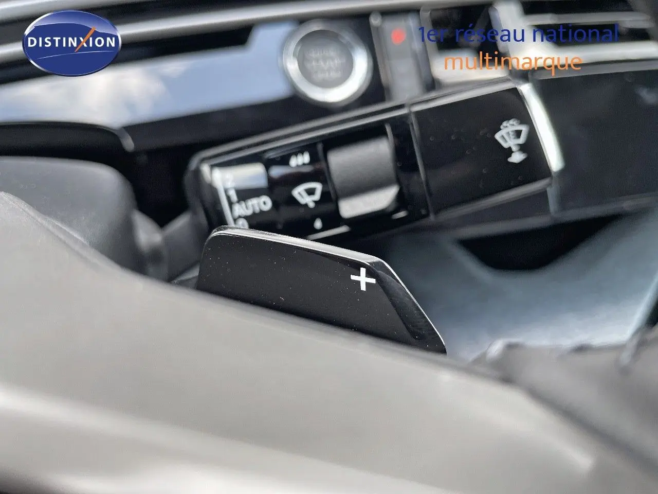 Gros plan sur la palette de passage de vitesses "+" côté droit du volant dans l'habitacle du Peugeot 3008 Hybrid 2025.
