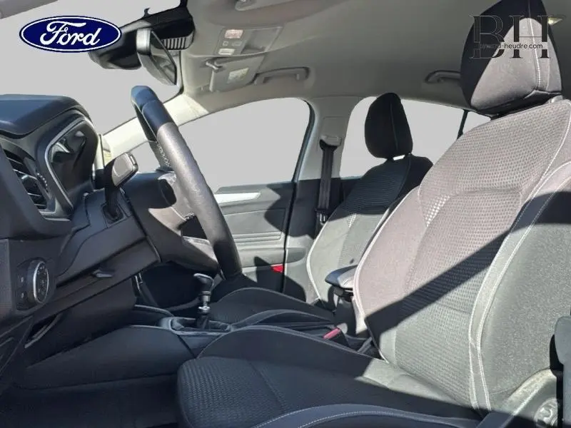 Intérieur avant de la Ford Focus 1.5 EcoBlue 2020, sièges tissu noir et volant cuir multifonction visible côté conducteur.