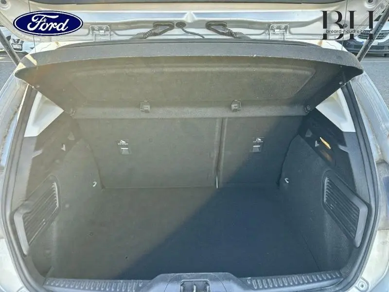 Coffre ouvert vu de l'arrière d'une Ford Focus gris lunaire métallisé, montrant un espace de chargement propre et spacieux.