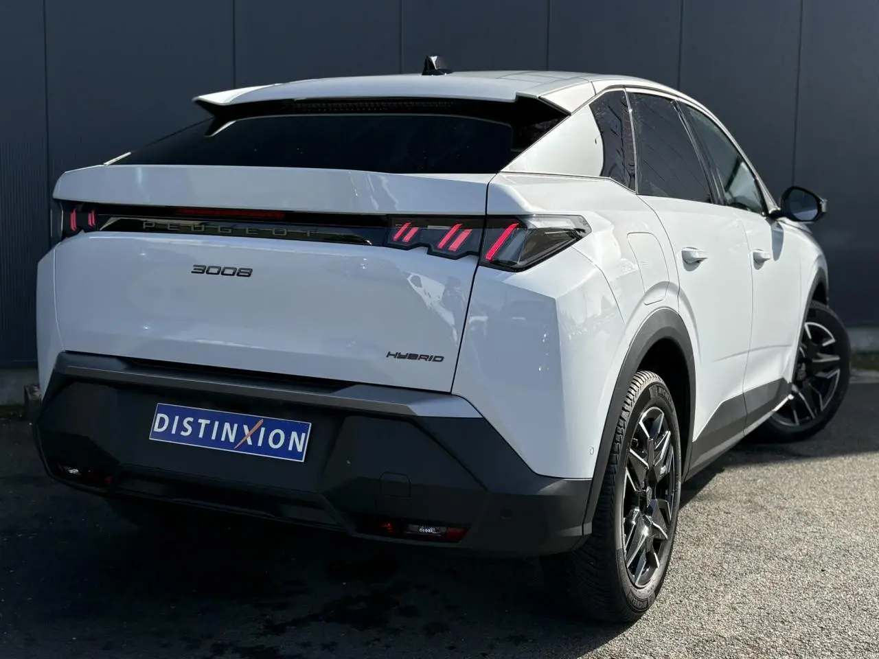 Vue 3/4 arrière droite du Peugeot 3008 Hybrid blanc Okenite avec feux arrière LED et jantes alliage noires.