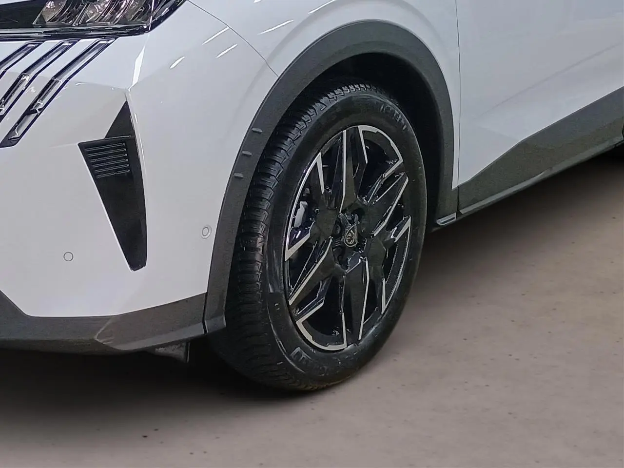 Gros plan sur le volant noir cuir avec commandes intégrées et partie gauche du tableau de bord gris clair du Peugeot 3008 Hybrid 2025.