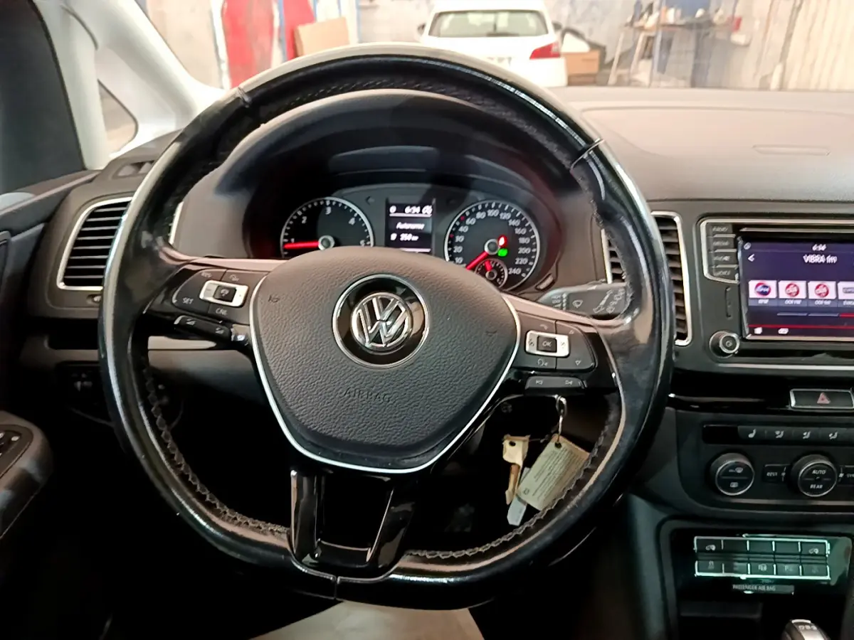 Vue intérieure centrée sur le volant cuir noir du Volkswagen Sharan 2017 avec tableau de bord et écran tactile visible.