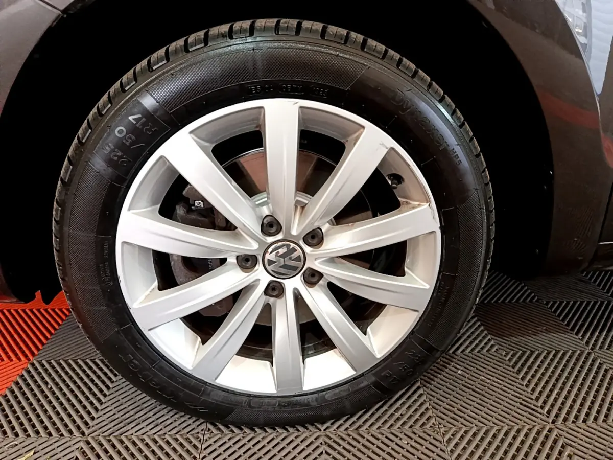 Gros plan sur la roue avant droite avec jante alliage argentée du Volkswagen Sharan marron 2017.