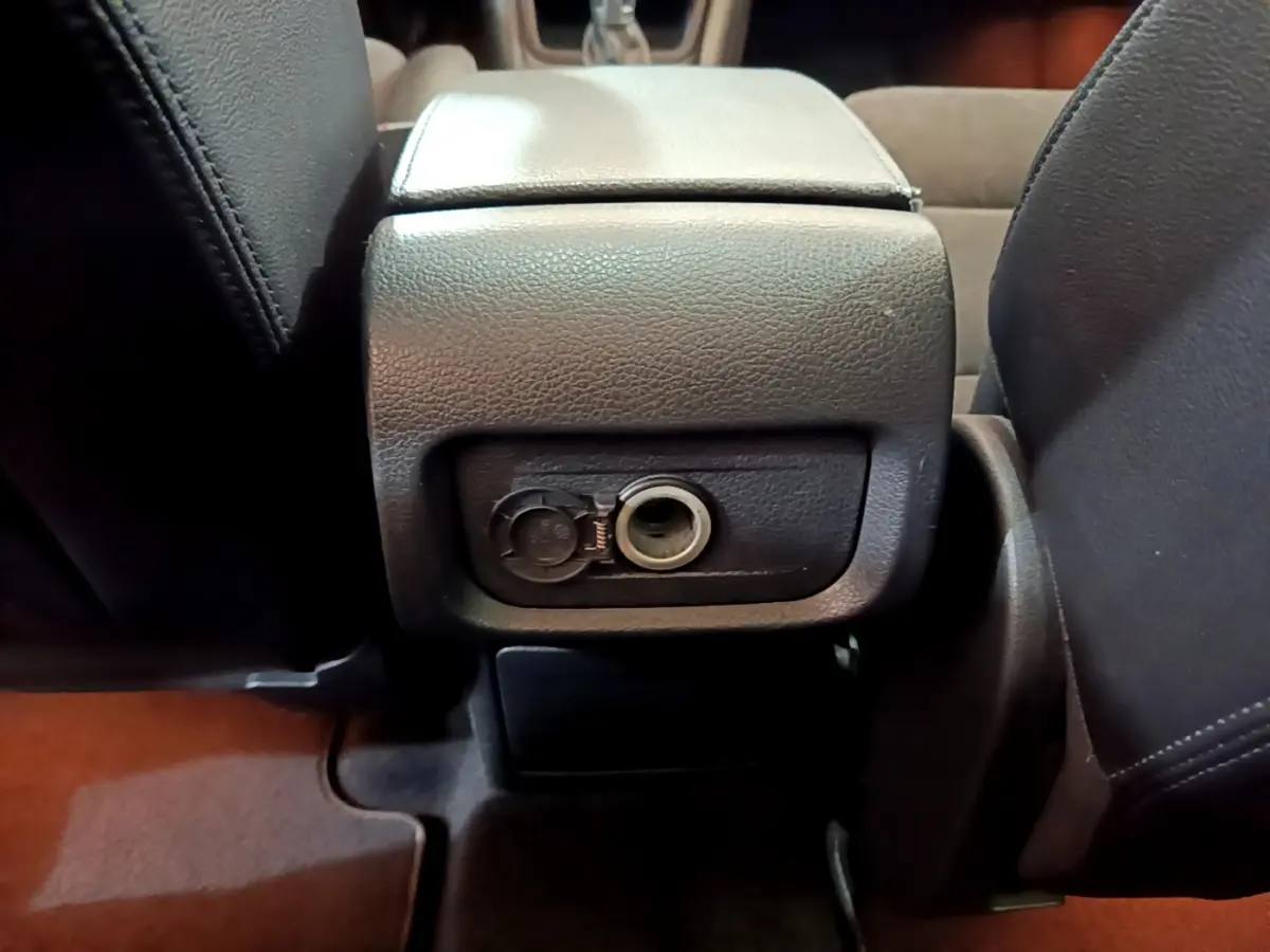 Prise 12V ouverte au dos de la console centrale, vue rapprochée de l'intérieur marron du Volkswagen Sharan 2017.