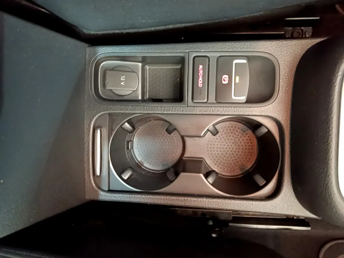 Vue rapprochée de la console centrale noire avec porte-gobelets et commandes électroniques d'une Volkswagen Sharan marron 2017.