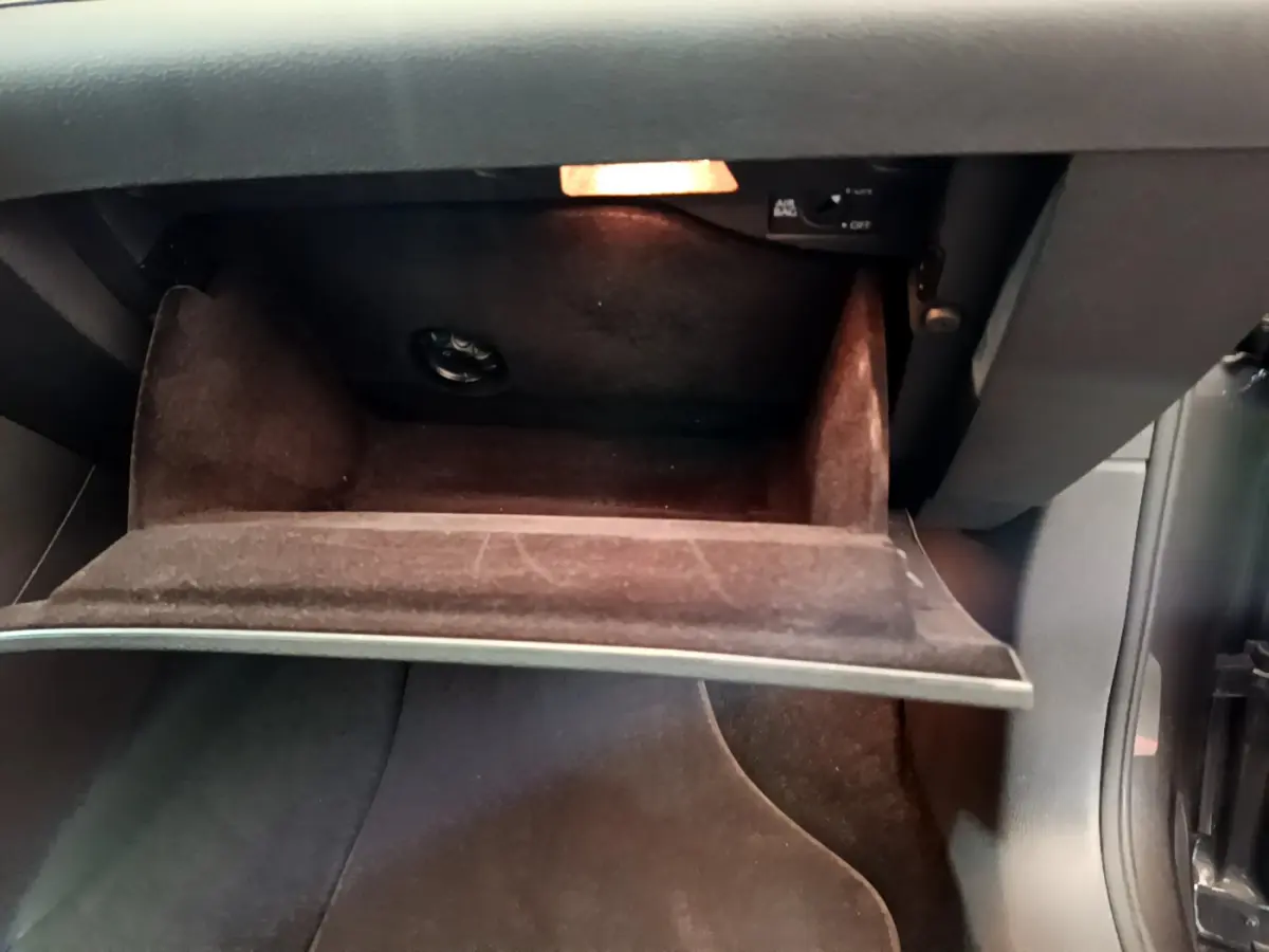 Gros plan sur la boîte à gants ouverte du Volkswagen Sharan 2017, intérieur noir avec éclairage intérieur allumé.