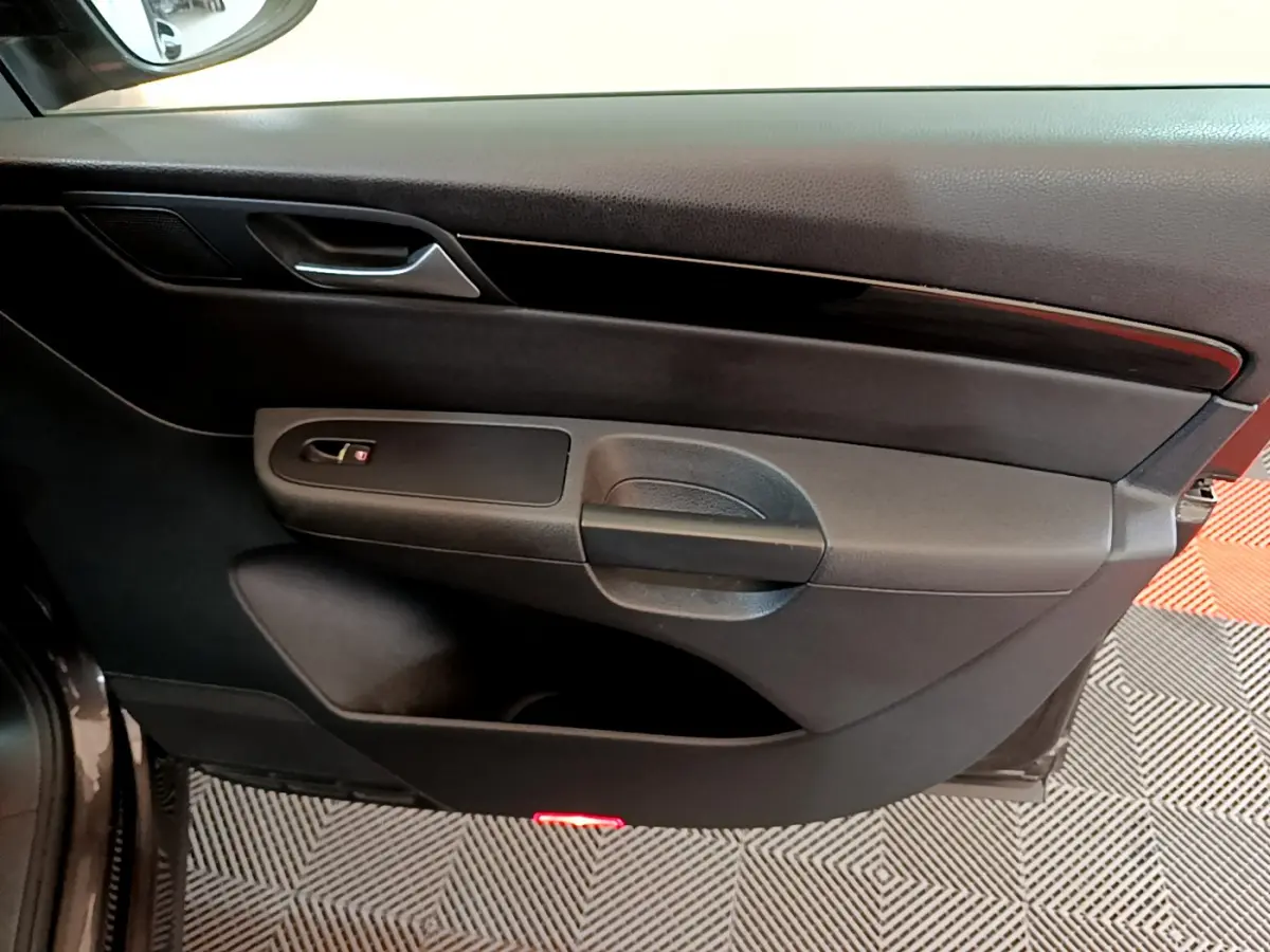 Vue rapprochée de la porte intérieure côté droit du Volkswagen Sharan marron, avec poignée et bande décorative noire.