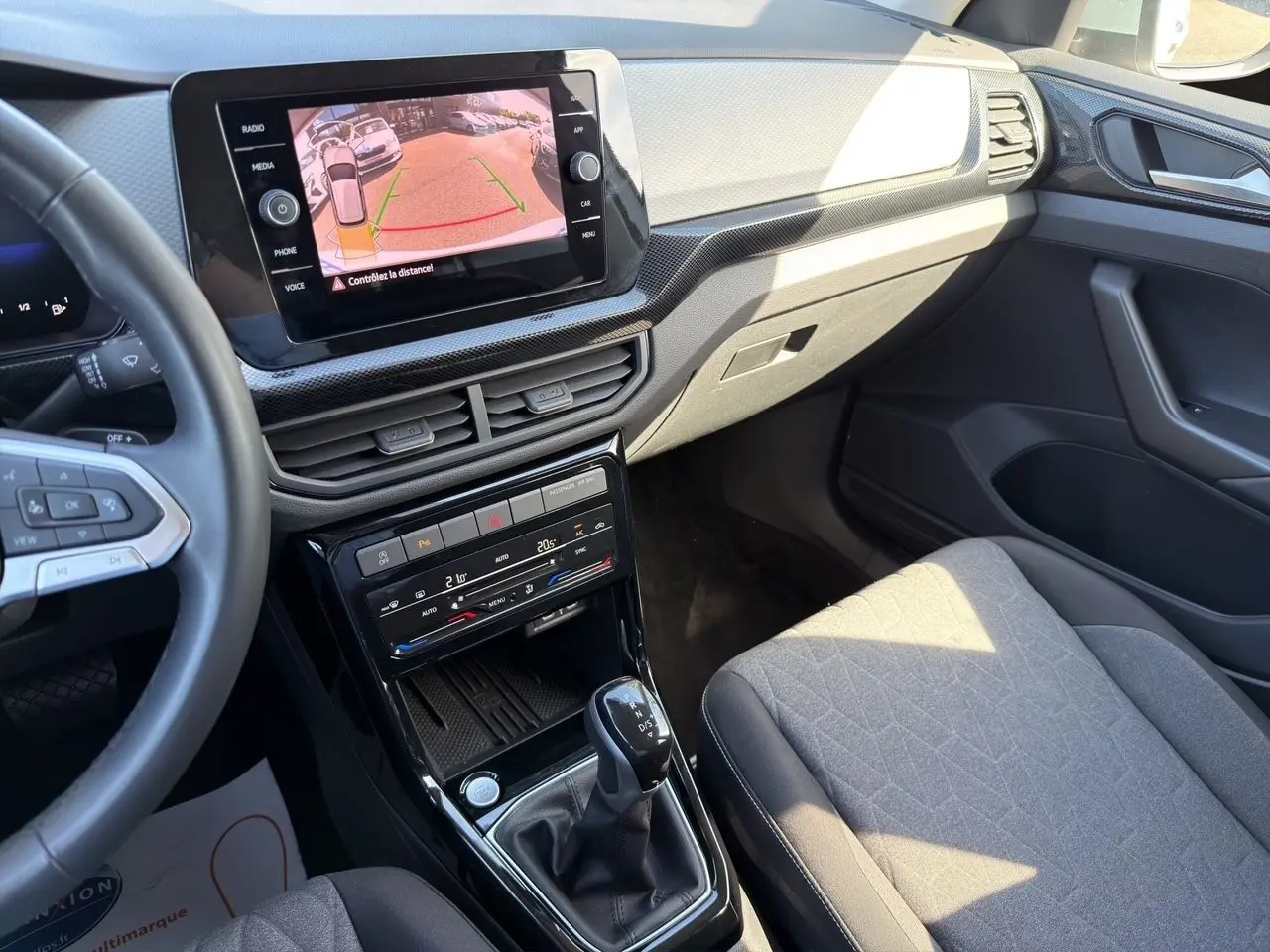 Vue intérieure côté passager du tableau de bord et console centrale noire du Volkswagen T-Cross 2025 avec écran tactile affichant la caméra de recul.