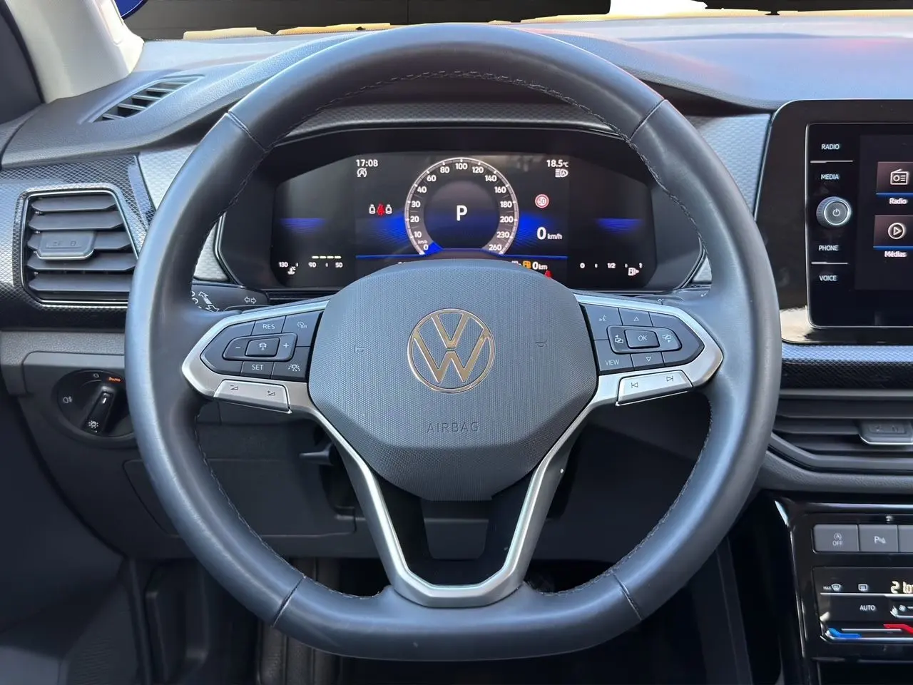 Vue rapprochée du volant cuir noir multifonction Volkswagen T-Cross 2025 avec tableau de bord digital et écran tactile.