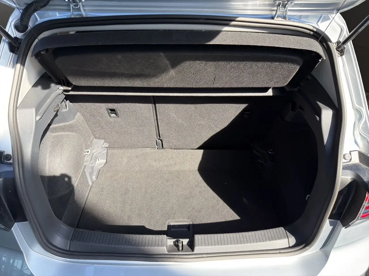 Coffre ouvert vu de l'arrière d'un Volkswagen T-Cross 2025 couleur reflet d'argent, intérieur noir.