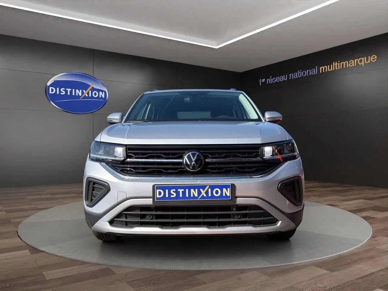 Volkswagen T-Cross 2025 couleur reflet d'argent vue de face en intérieur avec calandre noire et logo VW central.