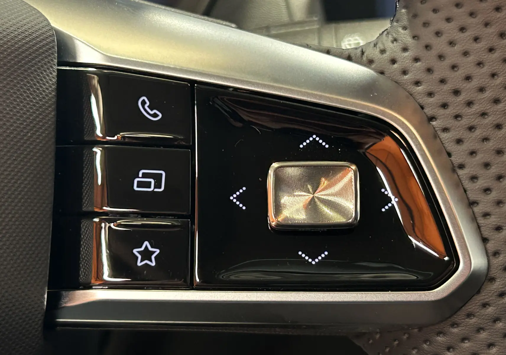 Gros plan sur les commandes au volant du MG ZS 1.5 Hybrid+ 197 Luxury, boutons noirs avec finition argentée et cuir perforé.