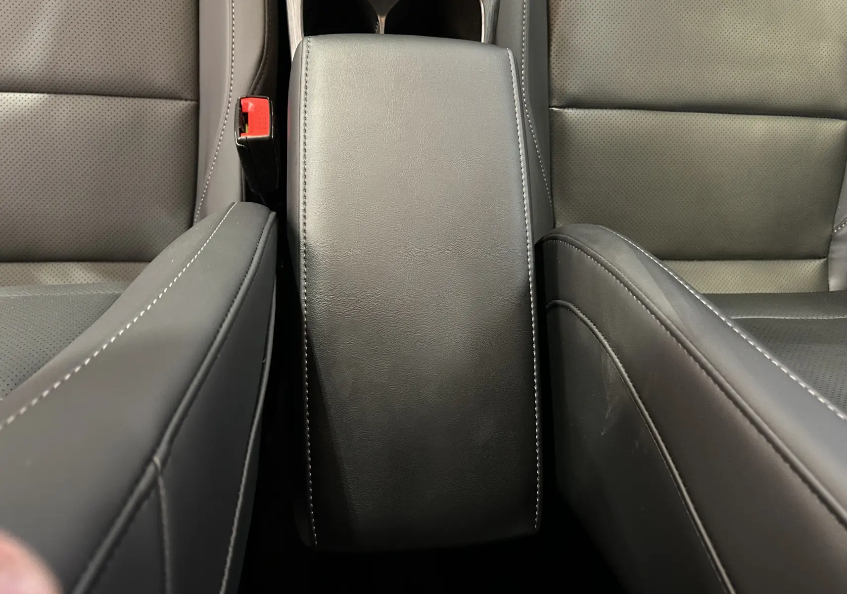 Vue rapprochée de l'accoudoir central en cuir noir avec surpiqûres blanches entre les sièges avant du MG ZS 1.5 Hybrid+ 197 Luxury.