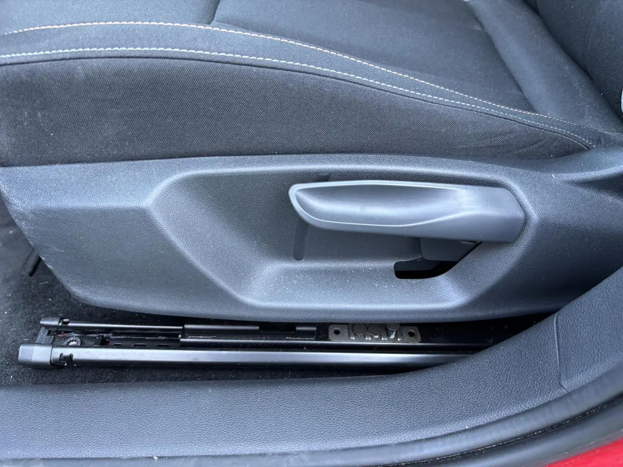 Détail de la commande manuelle de réglage du siège conducteur sur une SKODA SCALA rouge Velvet Metal 2024.