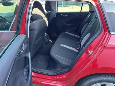 Vue intérieure côté arrière gauche d'une Skoda Scala rouge Velvet Metal, montrant la banquette arrière et les finitions des sièges noirs.