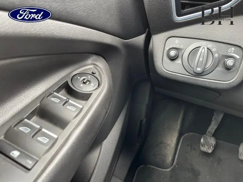 Vue rapprochée côté conducteur du tableau de bord et commandes de vitres du Ford Kuga gris Magnetic 2015.